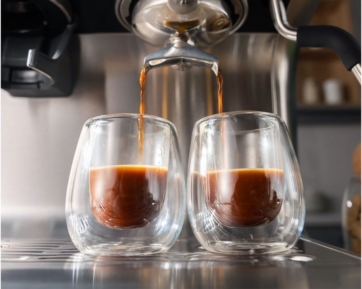 To espressoer løber fra portafiltrets tude ned i to dobbeltvæggede glas