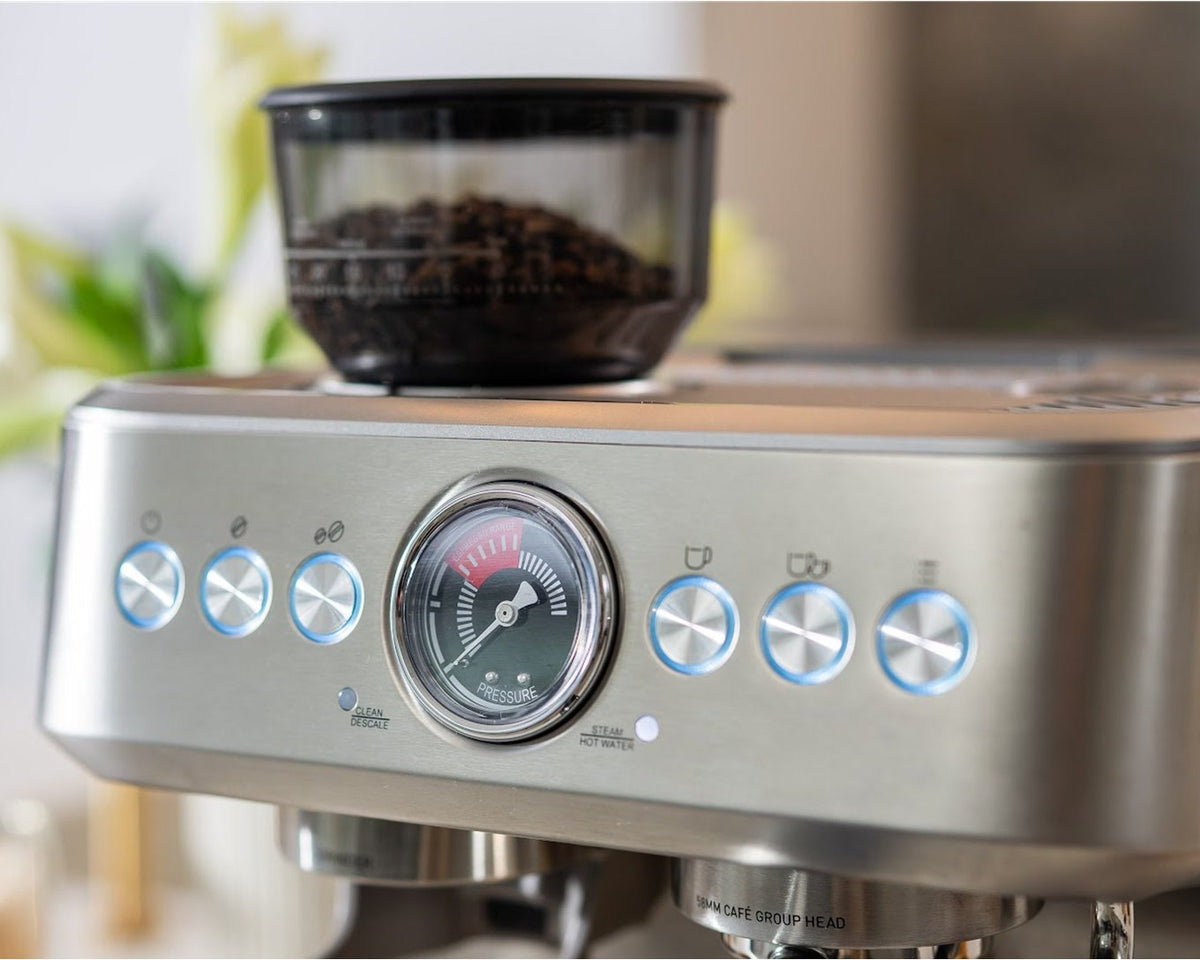 Fronten af en espressomaskine i stål med manometer, lysende knapper og bønnebeholder