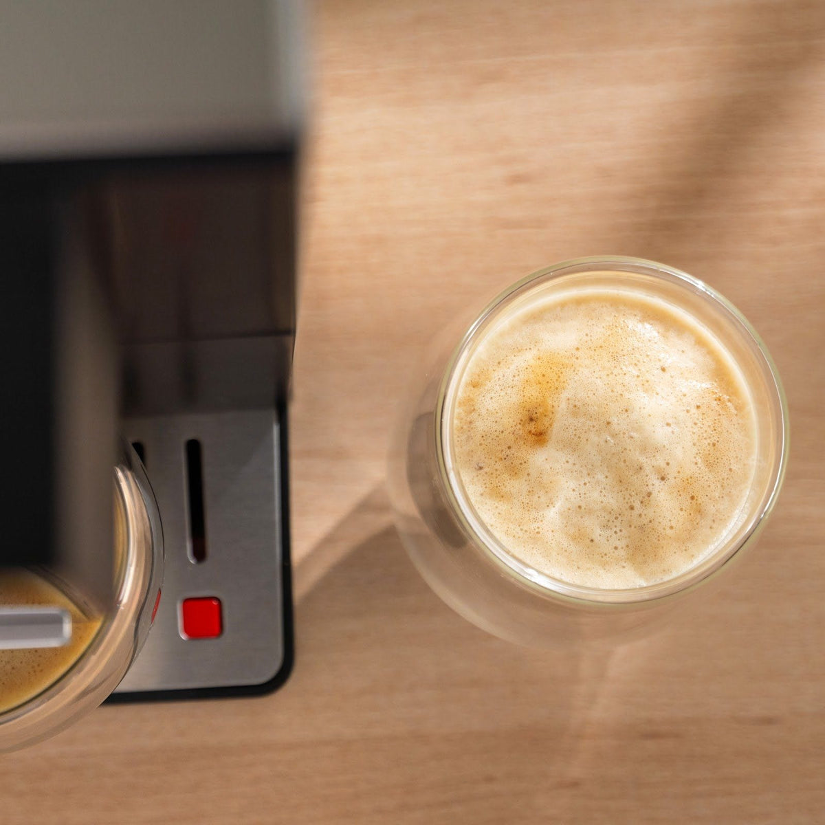 Latte i et glas set ovenfra, med et lyst, tæt lag mælkeskum